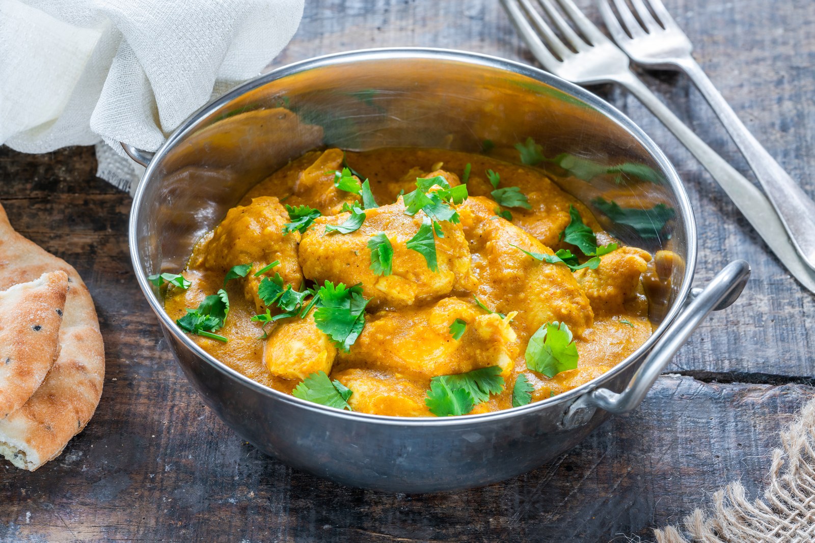 Chicken korma curry in a serving bowl with flatbread