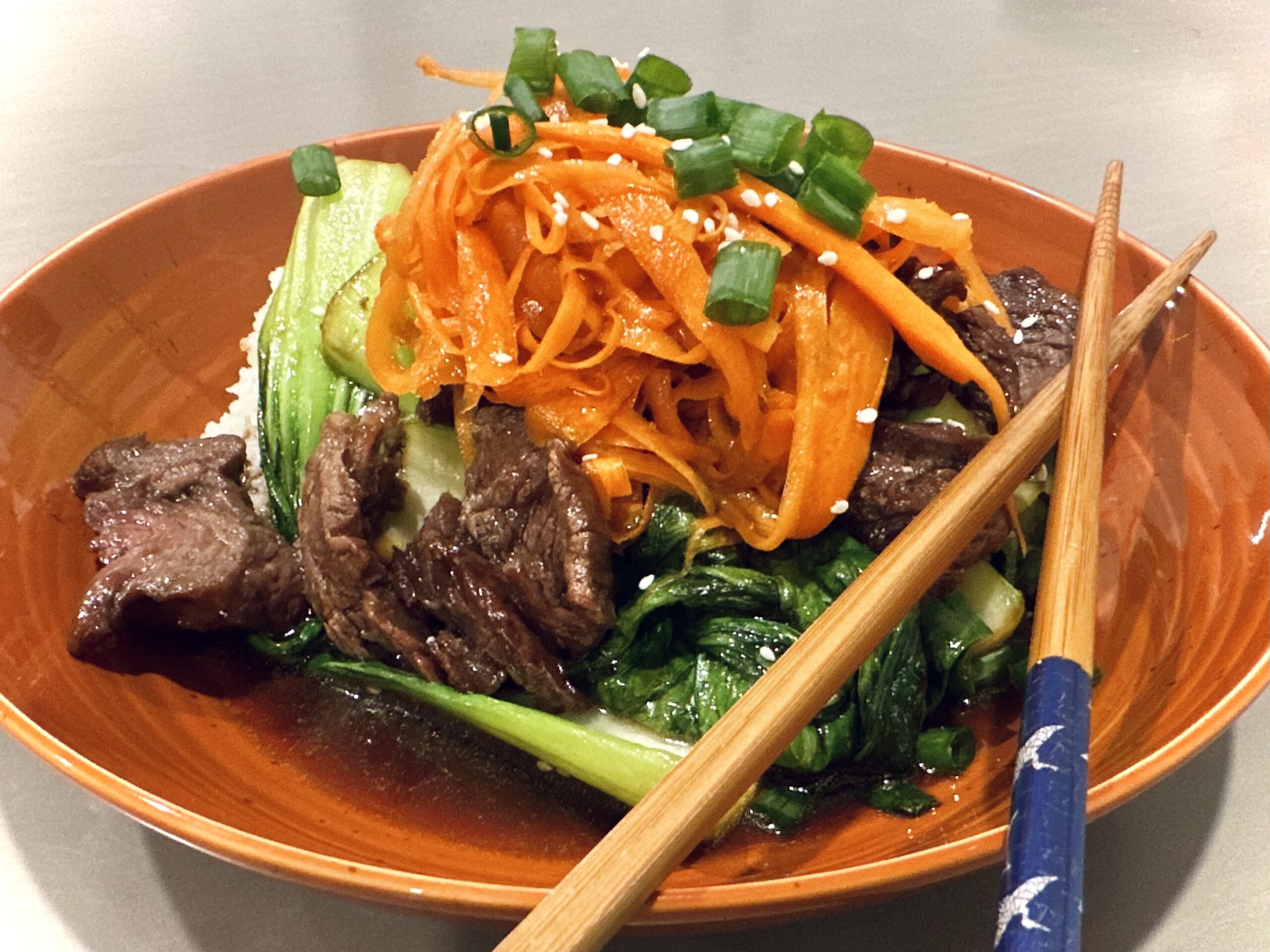 Japanese BBQ steak with bok choy and shredded carrots on rice