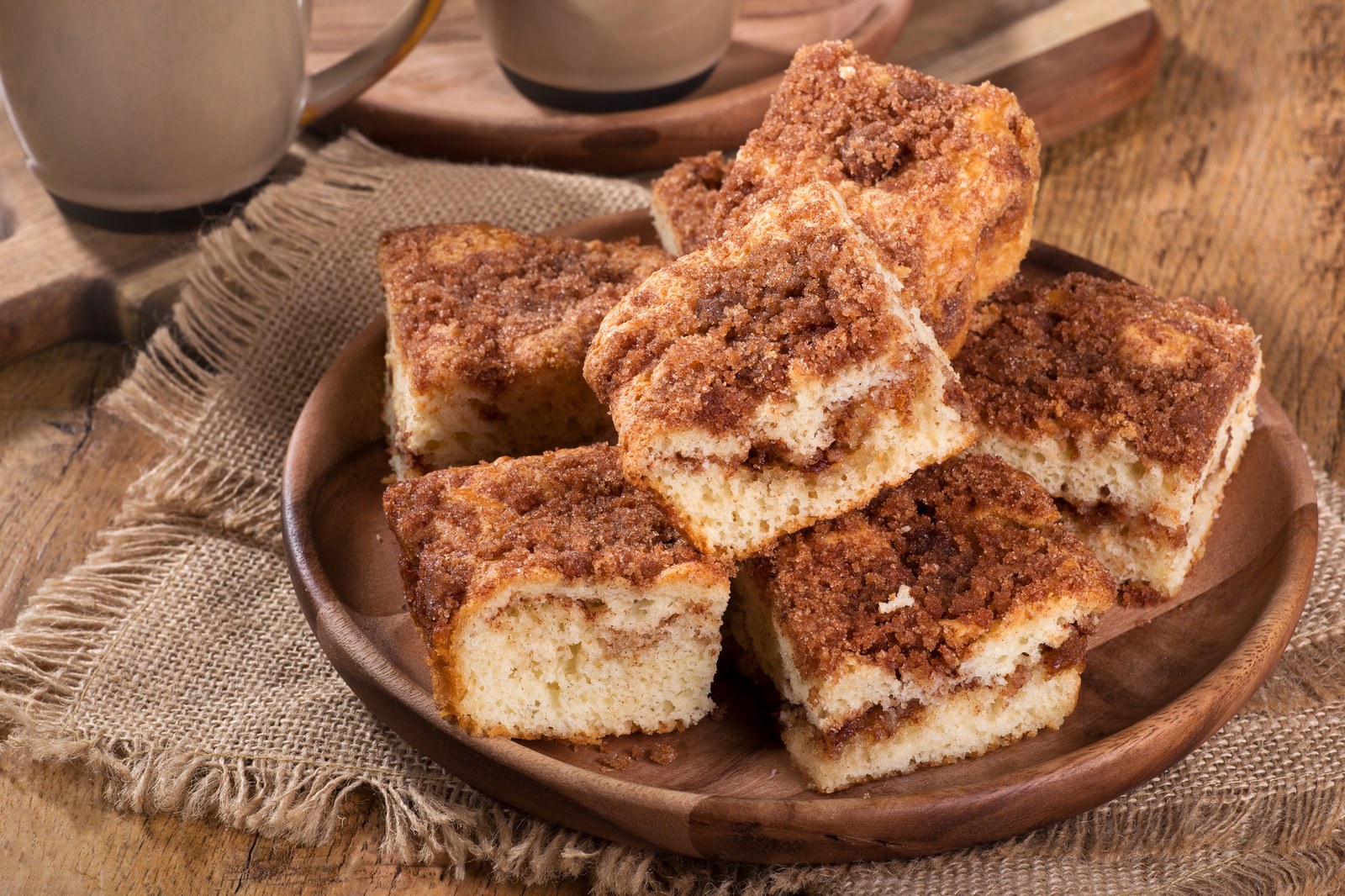 Squares of coffee cake with cinnamon streusel topping on a wooden plate