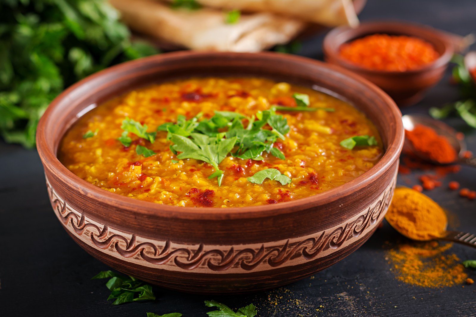 Bowl of dal tadka with yellow lentils in spiced broth, garnished with cilantro and red chili oil