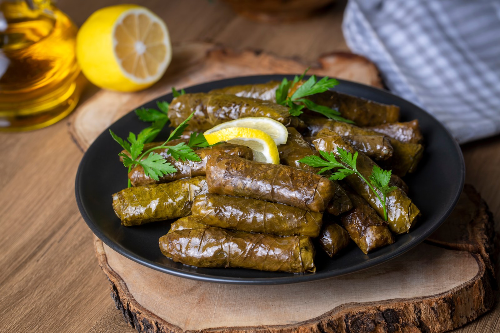 Plate of dolmades, rice stuffed grape leaves garnished with lemon slices and fresh parsley
