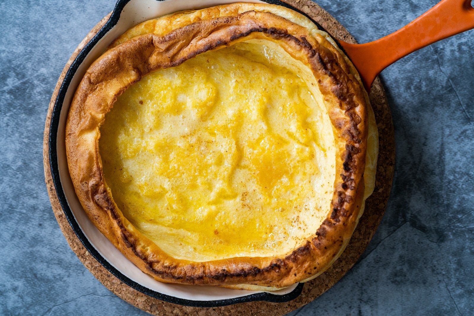 Puffy Dutch baby pancake baked in a cast iron skillet with dramatic risen edges and golden center