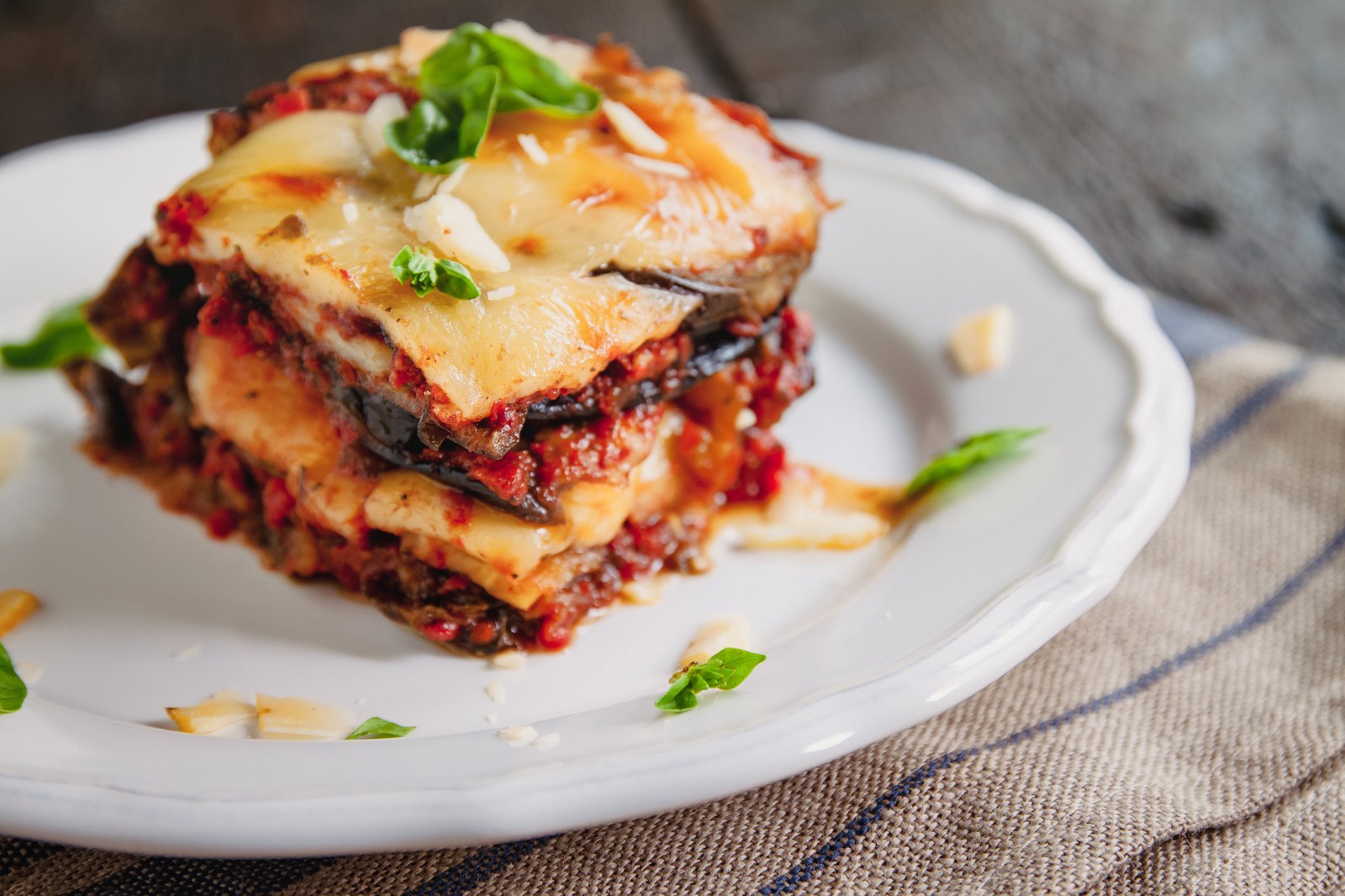 Slice of eggplant parmesan showing layers of breaded eggplant, marinara sauce, and melted mozzarella cheese