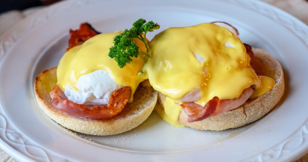 Eggs Benedict garnished with fresh herbs and cracked pepper