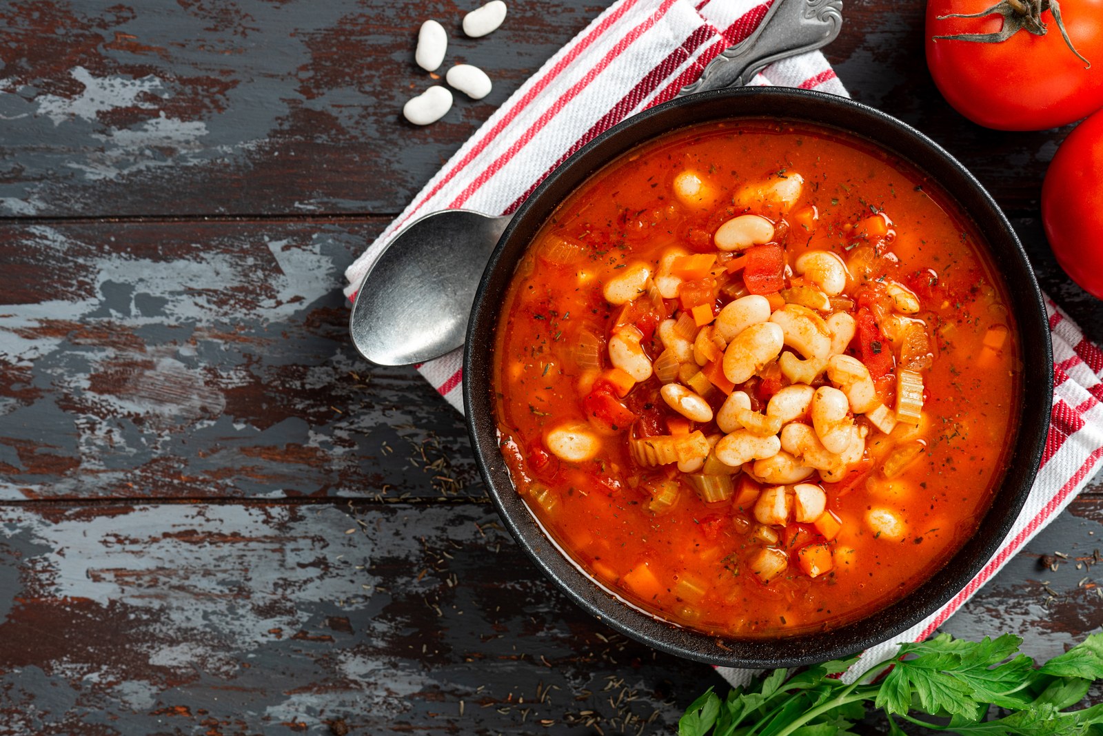 Bowl of fasolada Greek white bean soup with vegetables in tomato broth