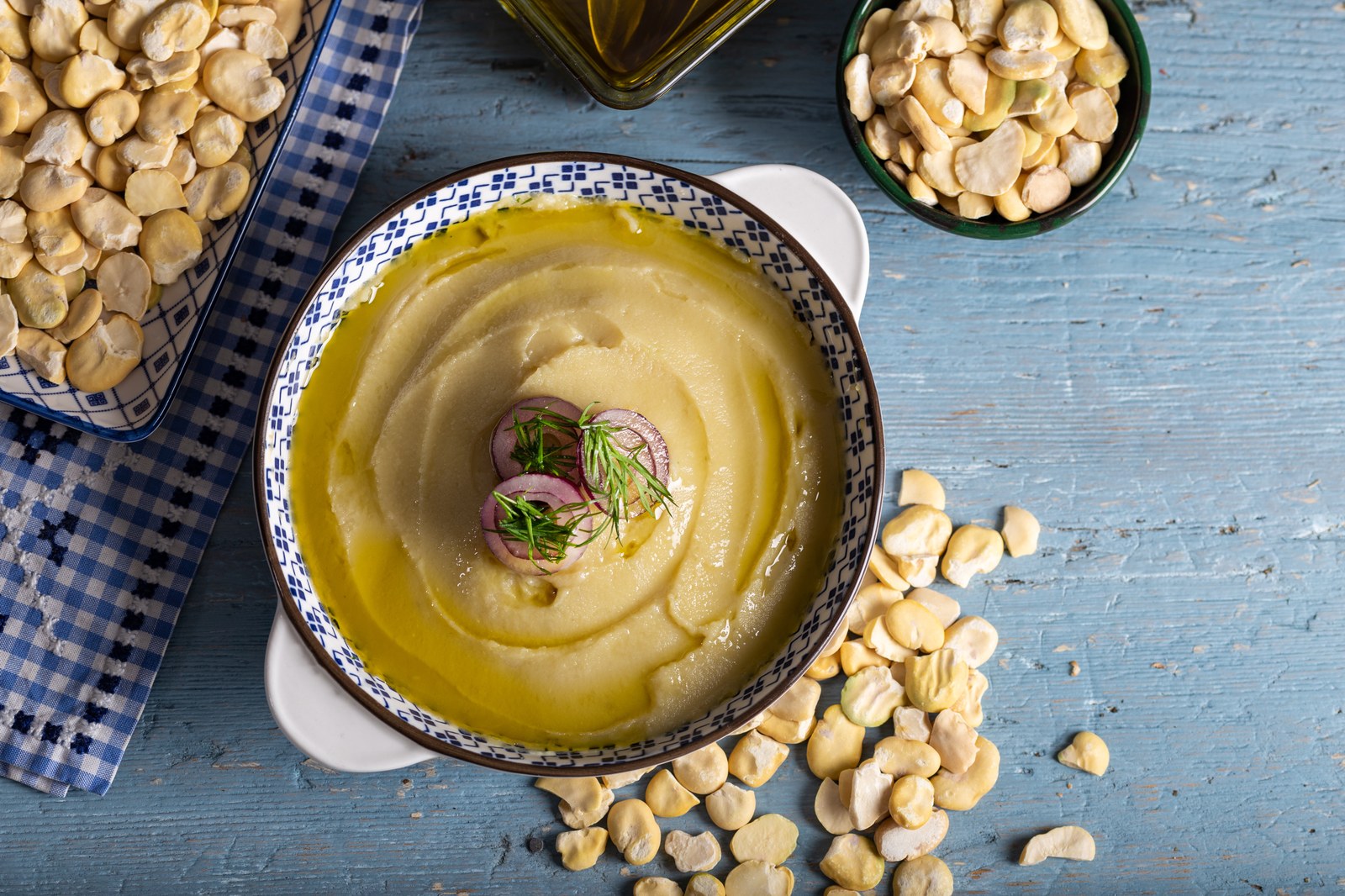 Bowl of Greek fava dip made from yellow split peas, drizzled with olive oil and garnished with herbs