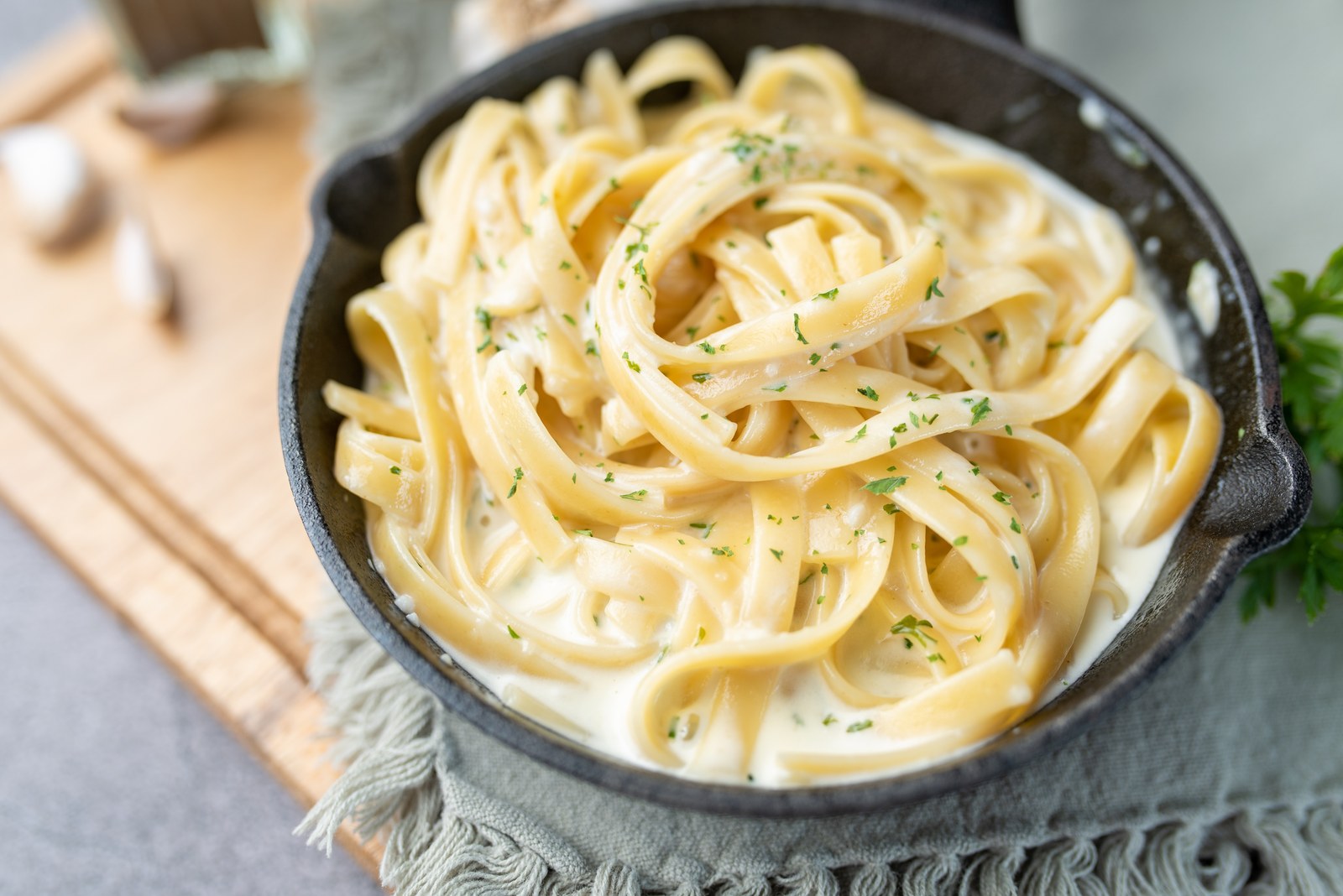Bowl of fettuccine alfredo pasta coated in creamy parmesan sauce, garnished with fresh parsley