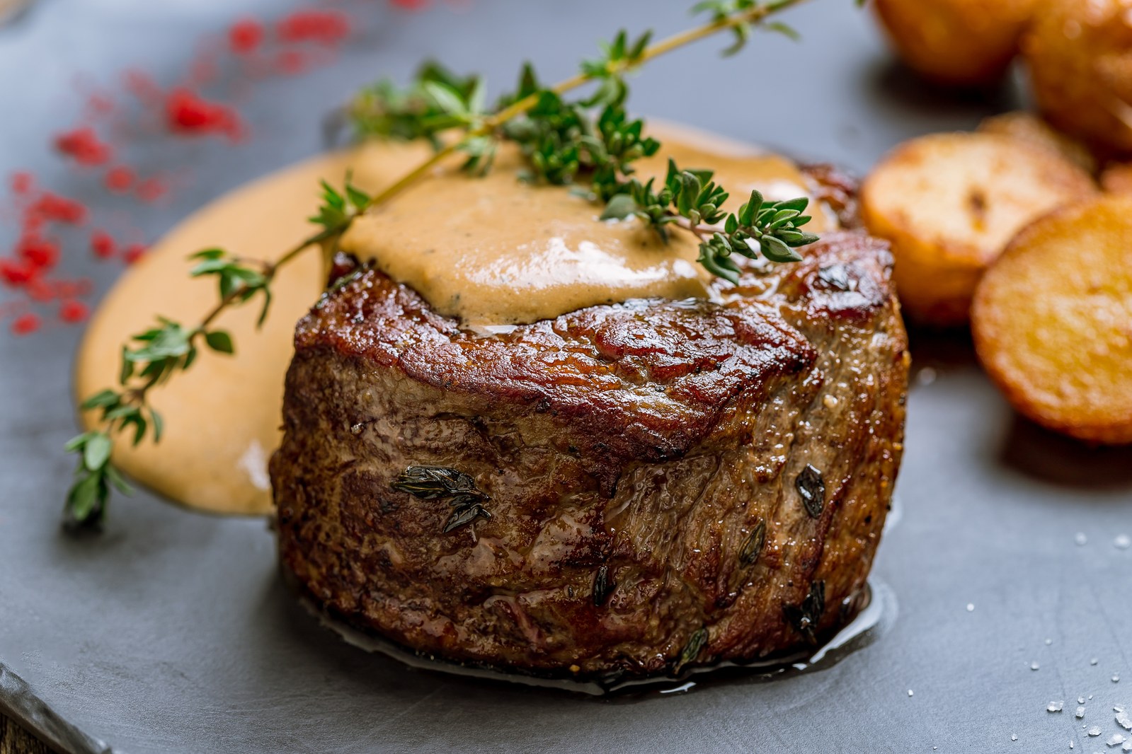 Thick filet mignon steak topped with herb compound butter and fresh thyme, served with mashed potatoes