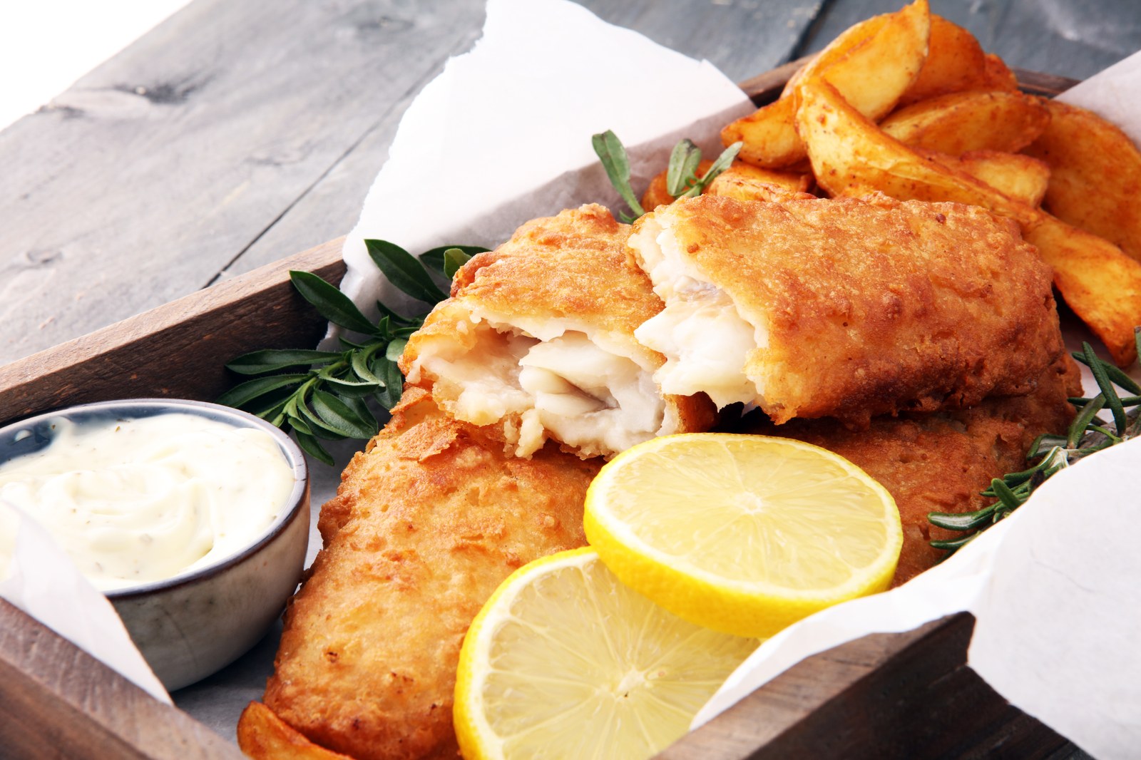 British fish and chips with golden battered fish fillet, thick cut chips, lemon slices, and tartar sauce