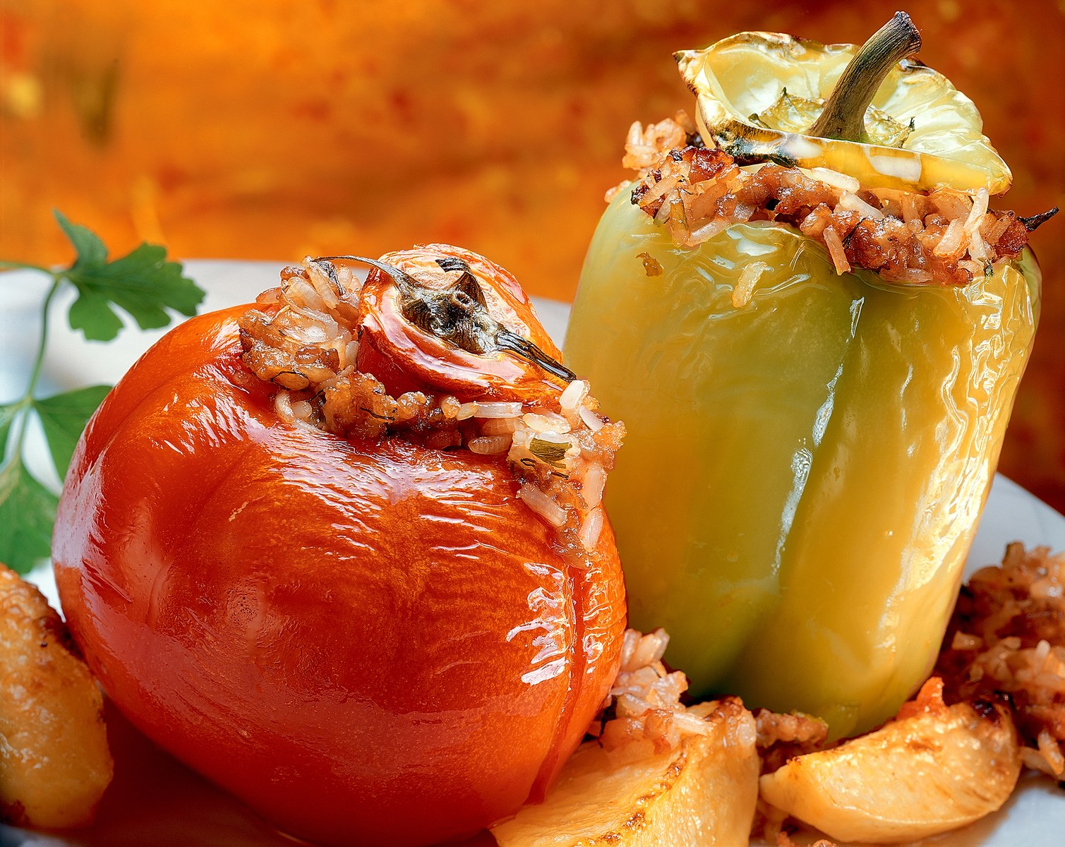 Greek gemista showing stuffed red and yellow bell peppers filled with herbed rice mixture, baked until tender