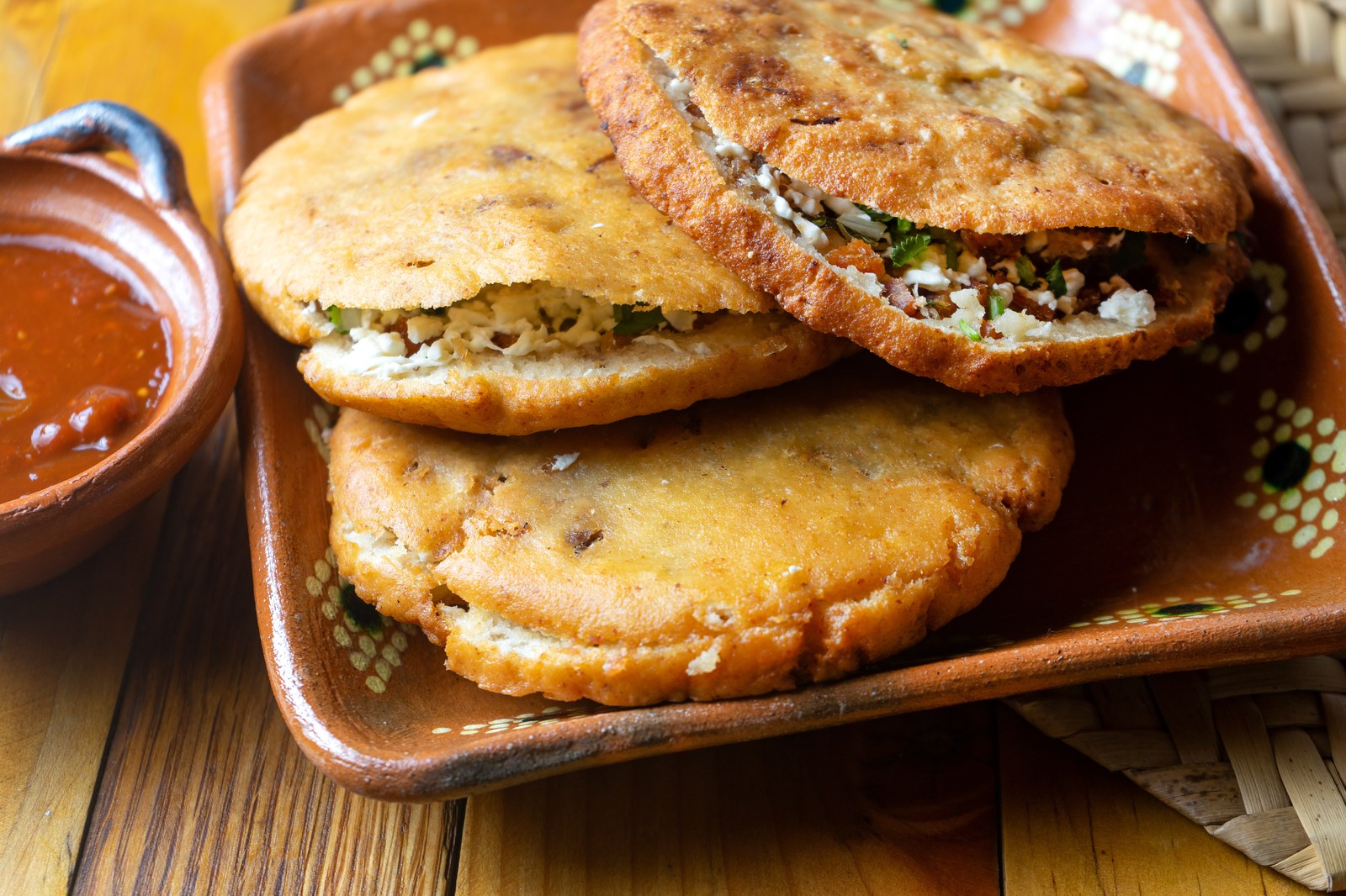 Stack of Mexican gorditas showing thick corn cakes with savory filling visible between the halves