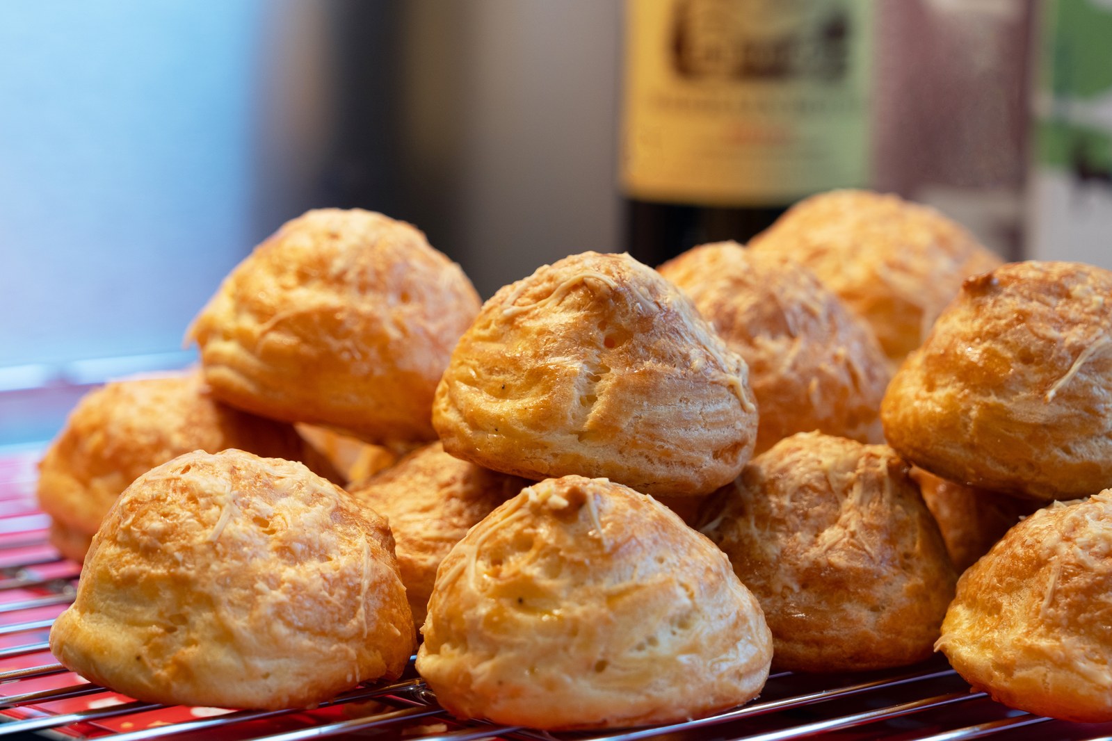 Pyramid of golden French gougères (cheese puffs) on a cooling rack, showing their airy crisp texture