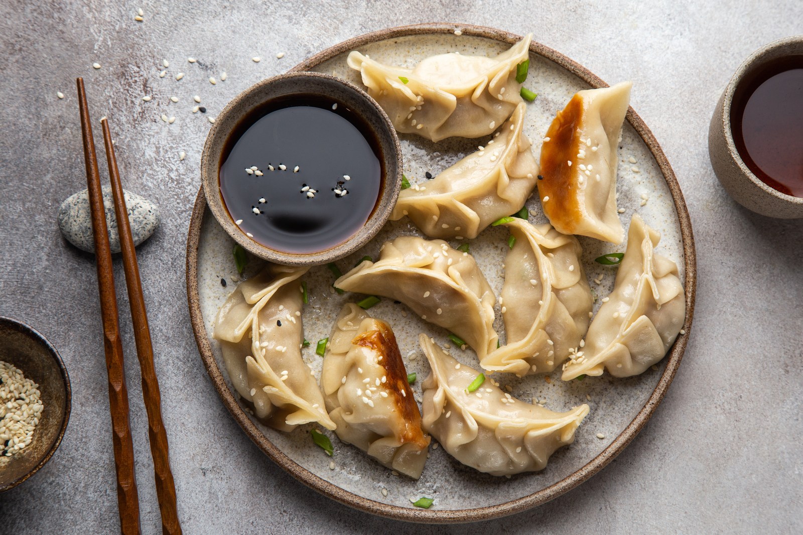 Pan fried gyoza dumplings arranged on a ceramic plate with a small bowl of dipping sauce