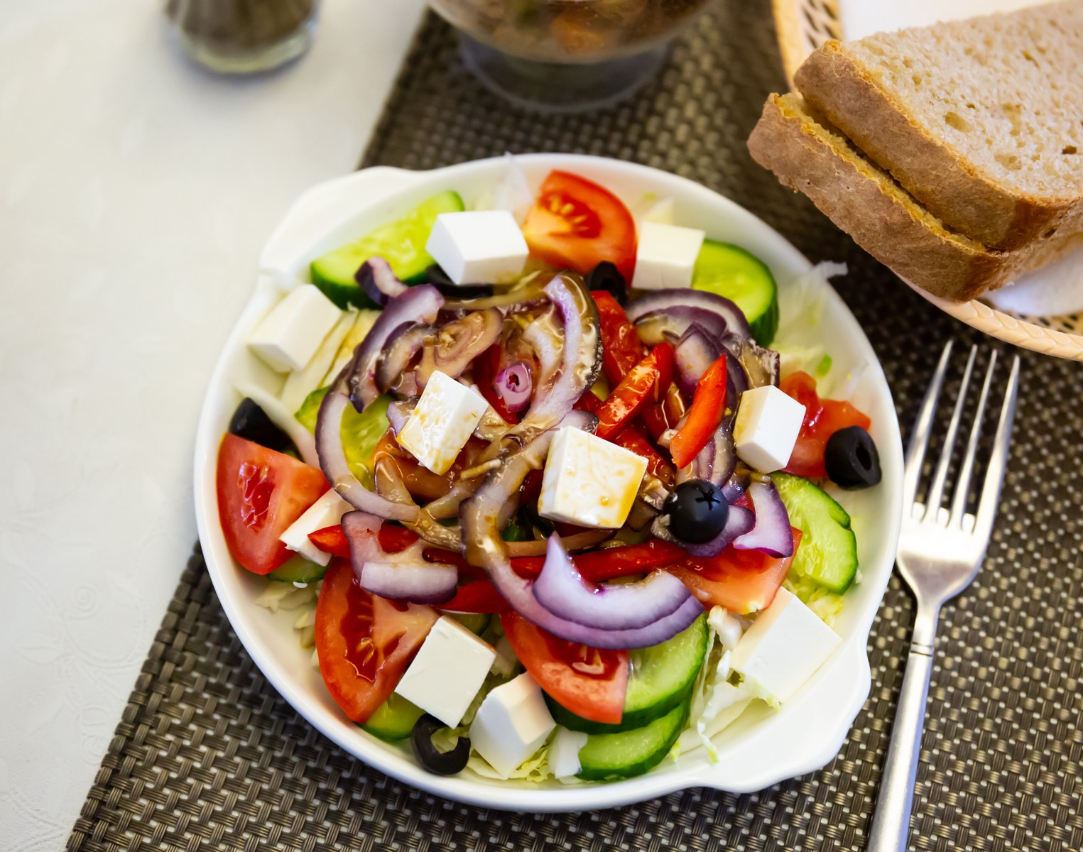 Greek horiatiki salad with tomatoes, cucumbers, red onions, feta cheese, and black olives drizzled with olive oil