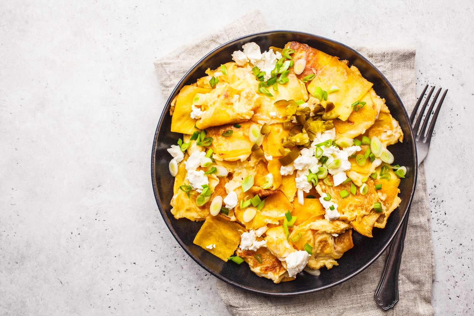 Scrambled eggs mixed with crispy tortilla strips, topped with queso fresco and sliced almonds