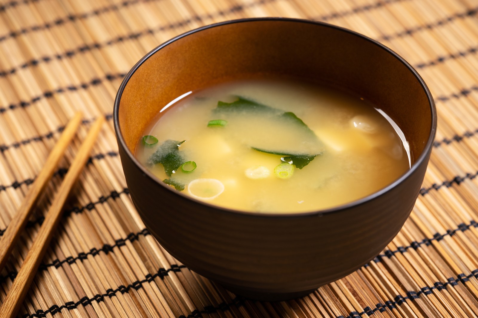 Traditional miso soup in a black lacquer bowl with tofu, wakame seaweed, and scallions