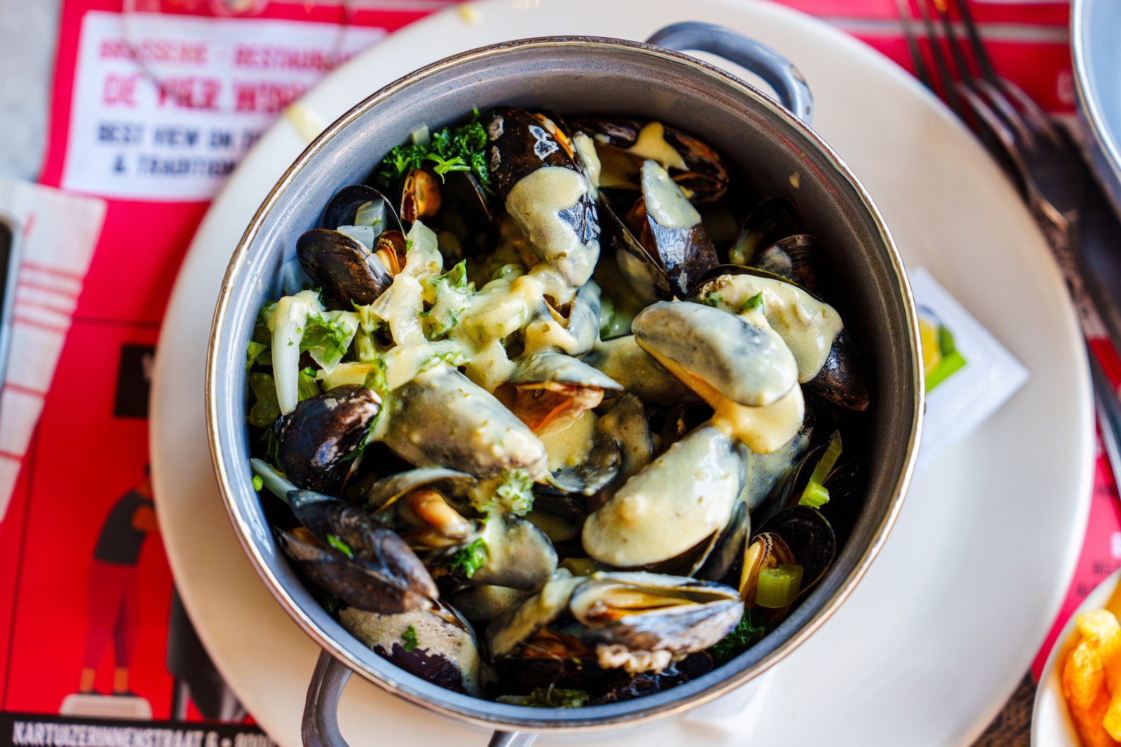 Black mussels in their shells covered with a creamy white wine sauce and herbs