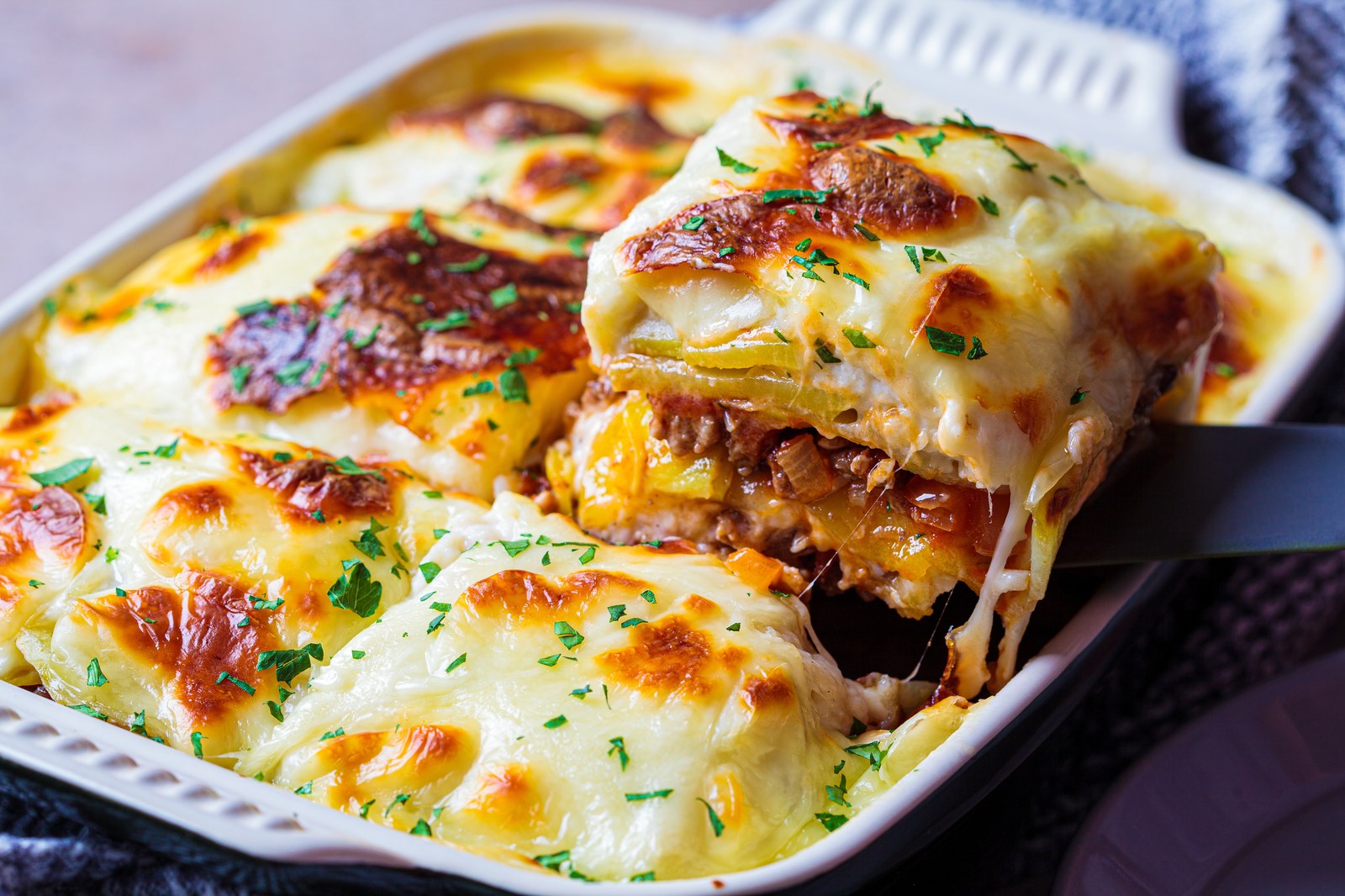 Baked Greek casserole with layers of eggplant, meat sauce, and golden béchamel top