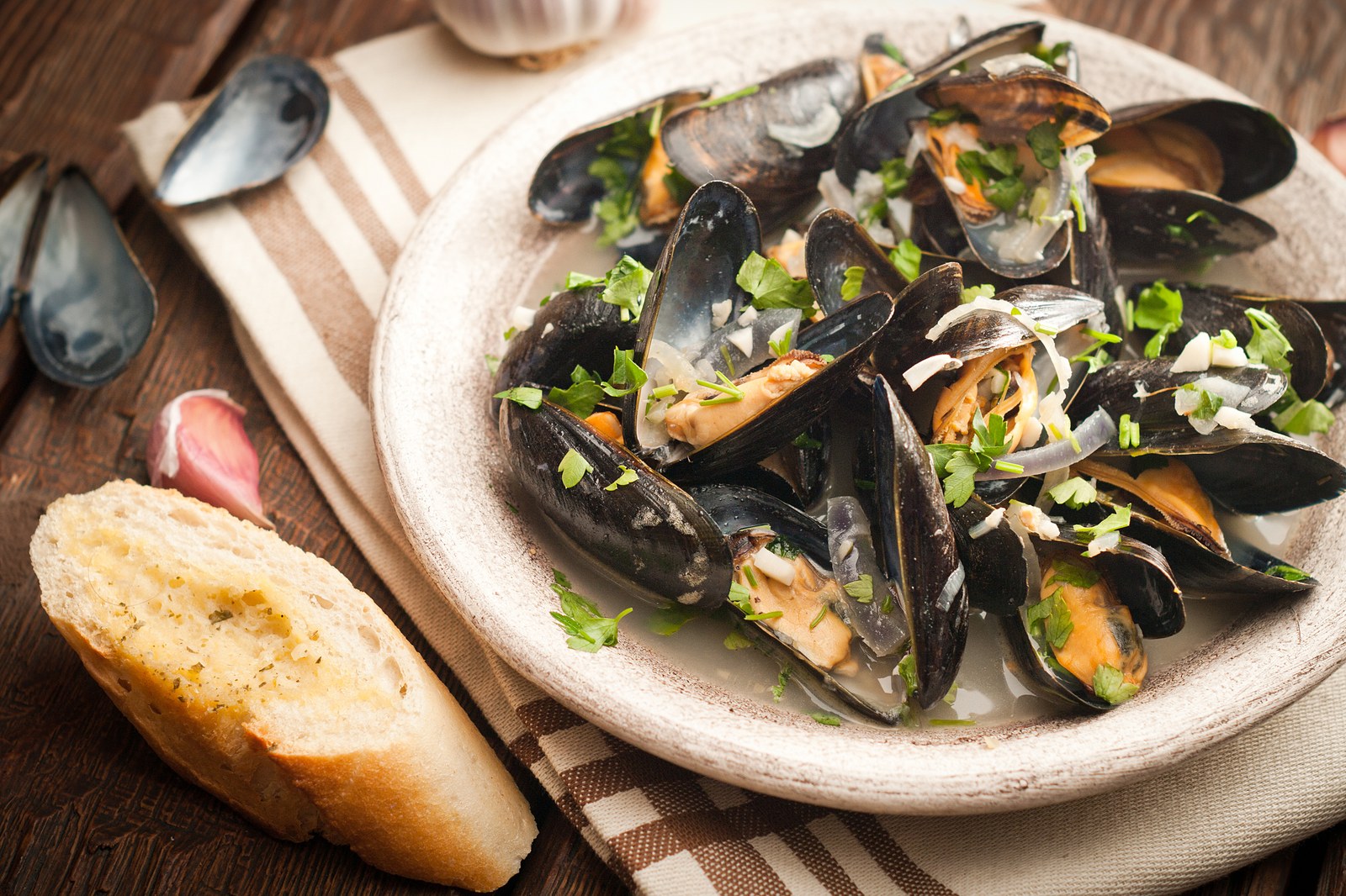 Steamed mussels with parsley and shallots served alongside a baguette