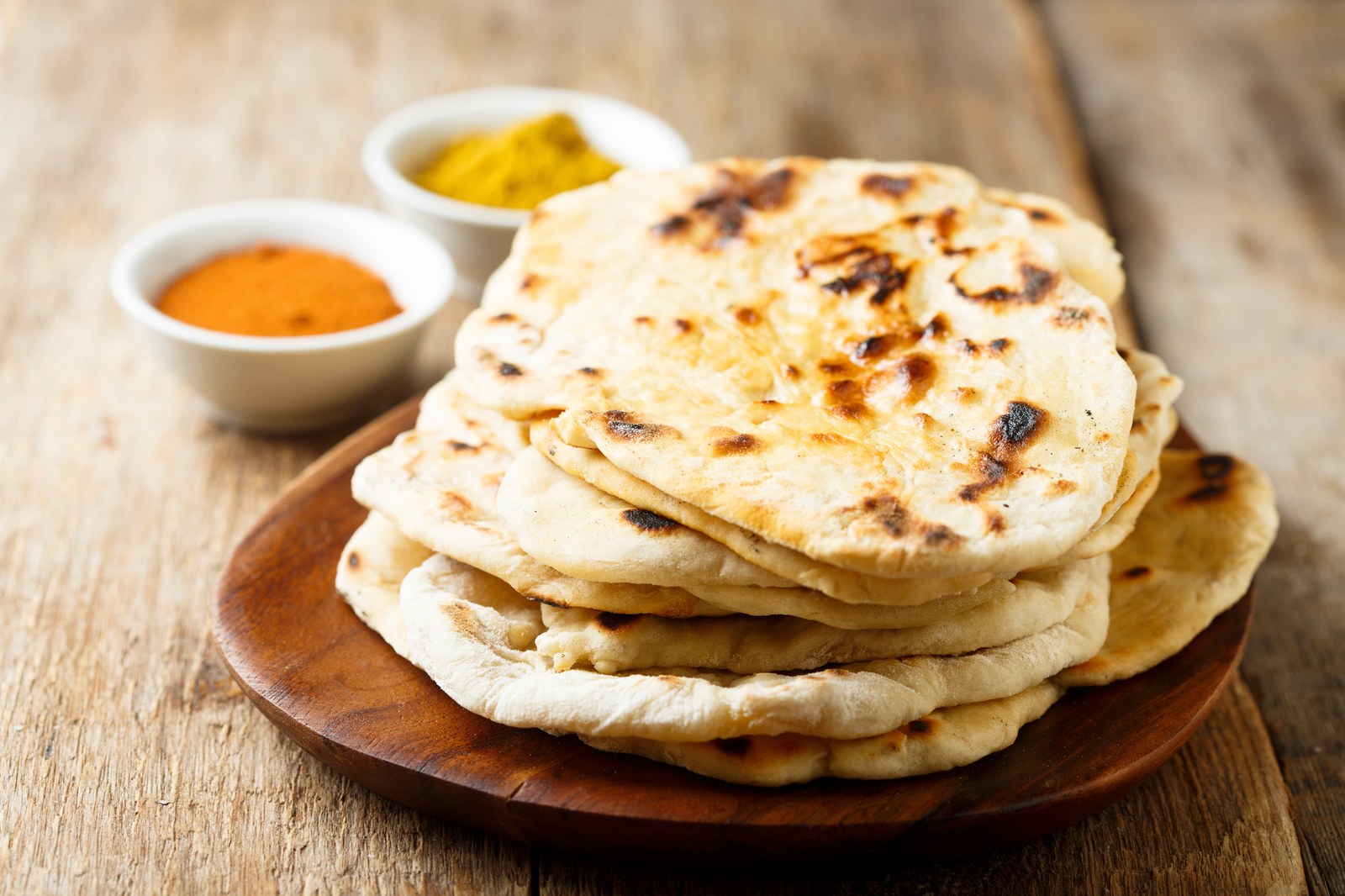 Stack of charred Indian flatbreads with visible air bubbles and browned spots