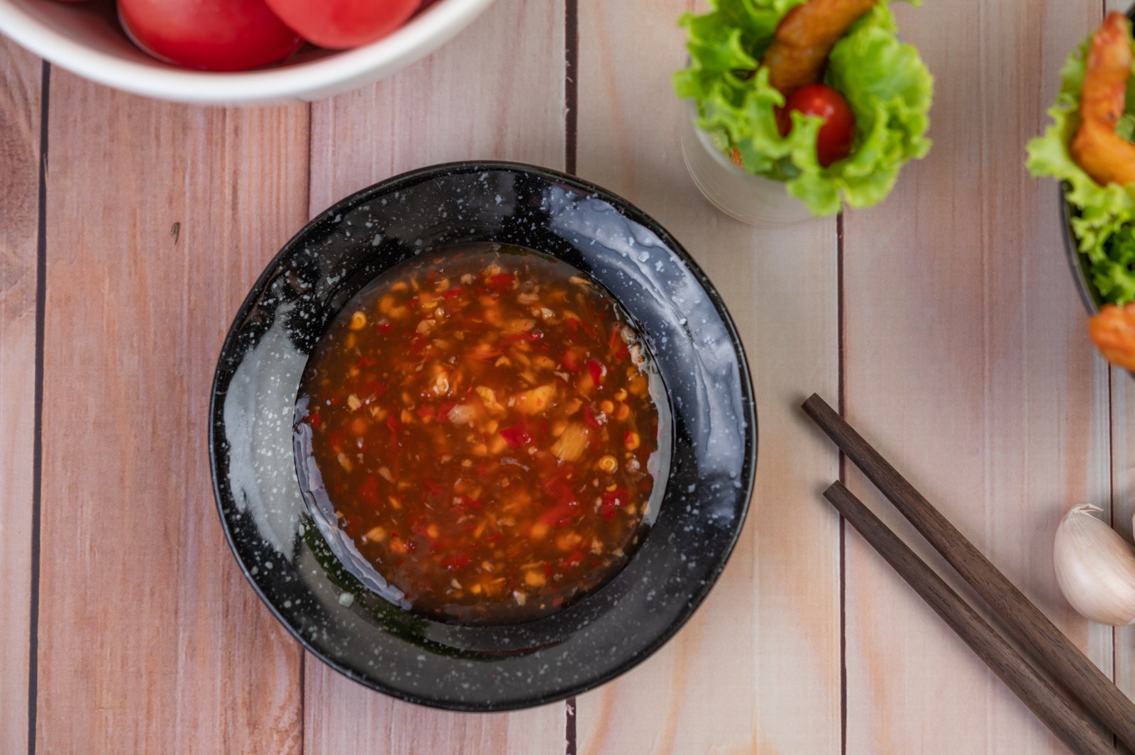 Bowl of spicy Thai dipping sauce with visible chilies and herbs