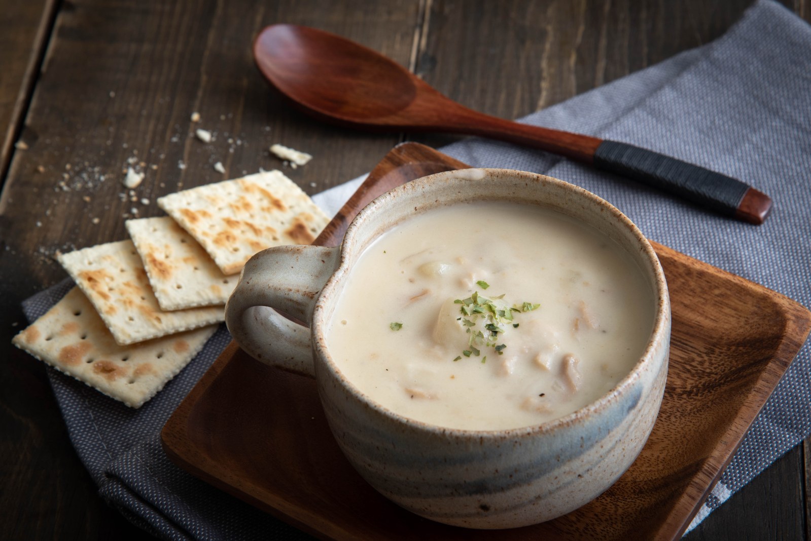 Creamy white soup with chunks of clams and potatoes served with crackers