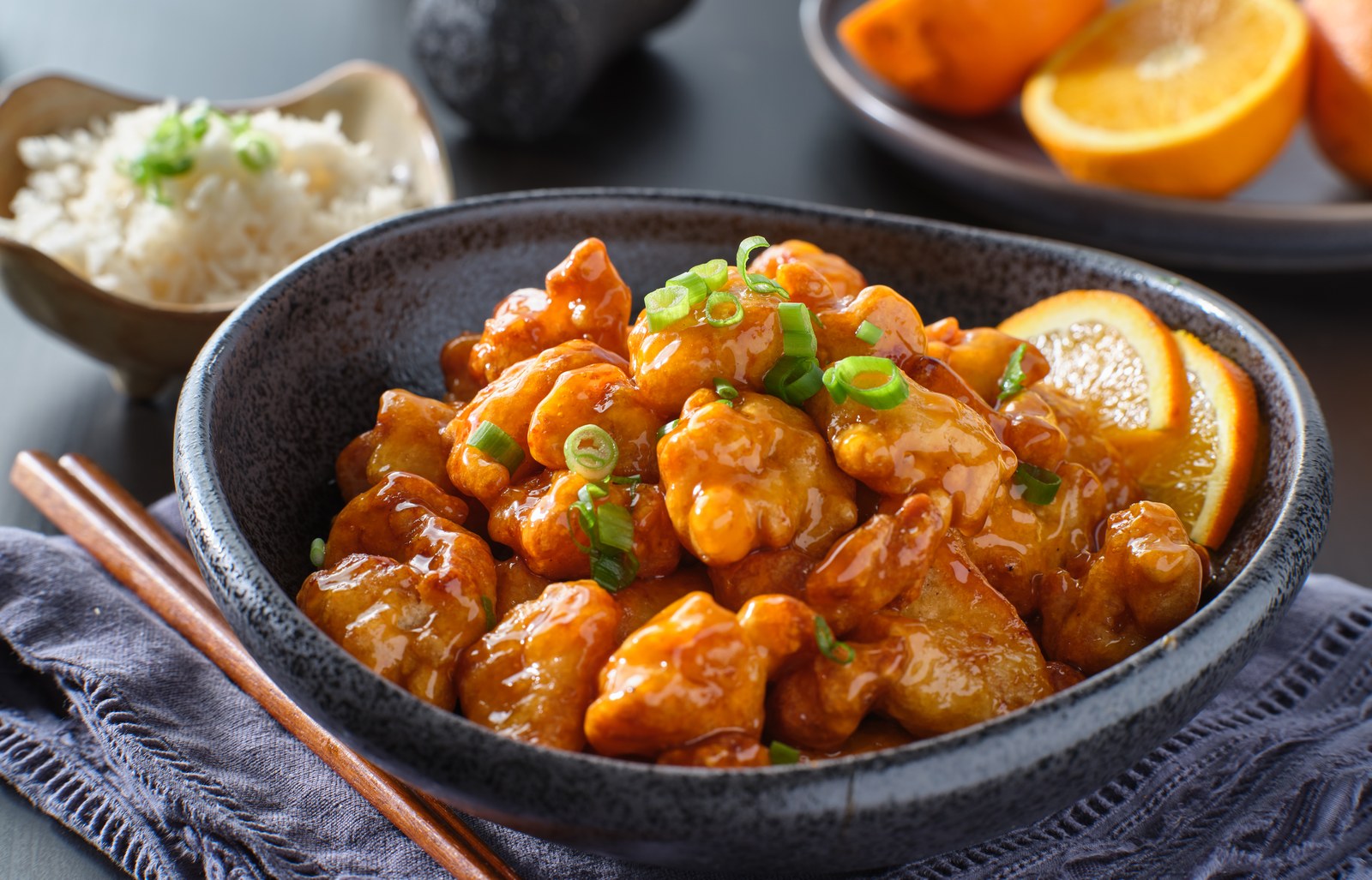 Crispy orange chicken pieces in glossy sauce with scallions and sesame seeds