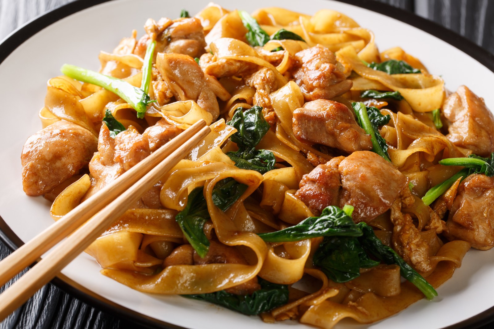 Wide rice noodles stir fried with chicken, Chinese broccoli, and dark soy sauce