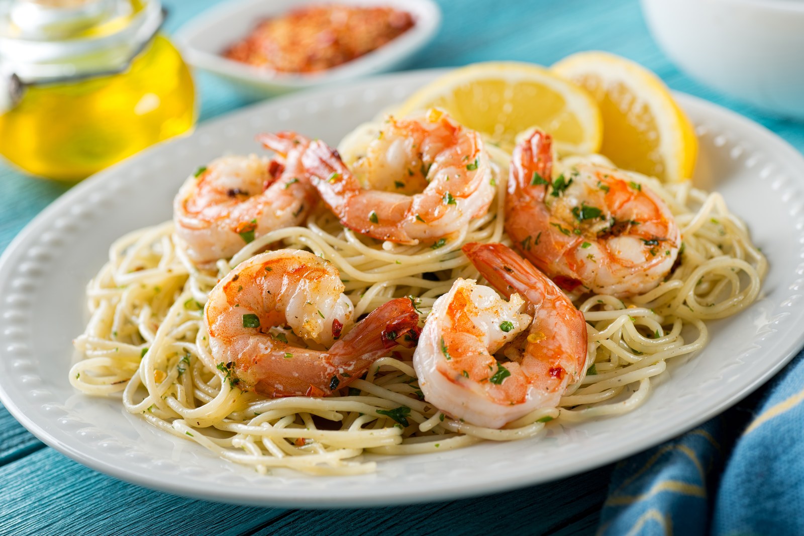 Linguine pasta topped with sautéed shrimp in garlic butter sauce, garnished with fresh parsley and lemon slices on a white plate