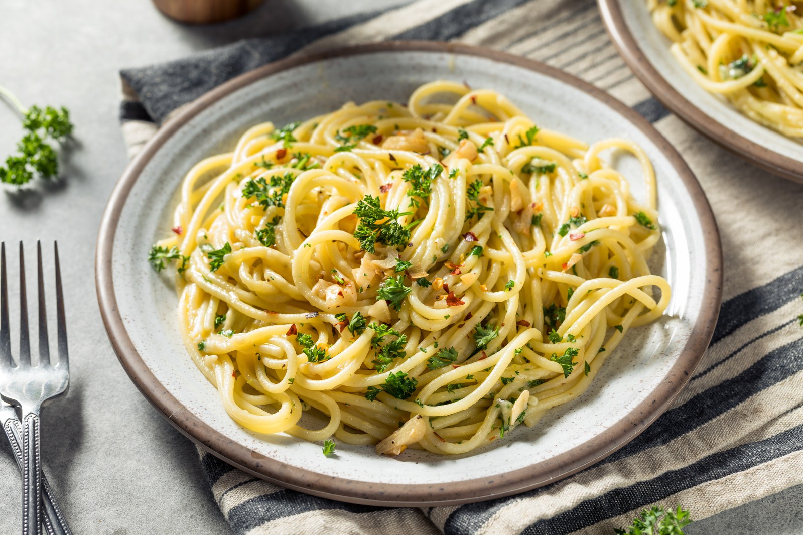 Spaghetti tossed with garlic, olive oil, and parsley on a ceramic plate