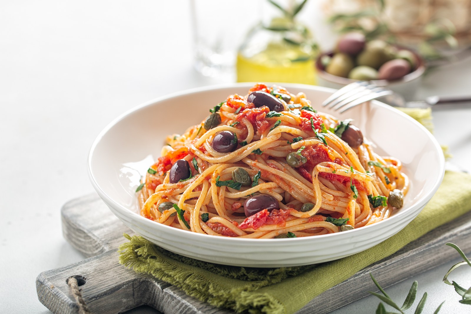 Spaghetti in tomato sauce with olives, capers, and fresh parsley