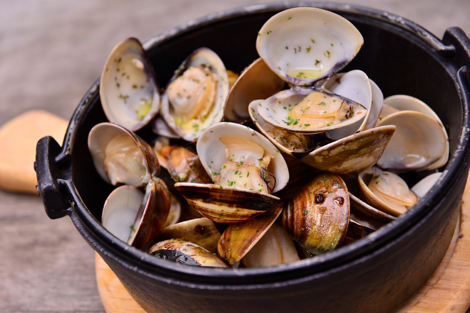 Steamed clams in a black cast iron pot, garnished with fresh parsley