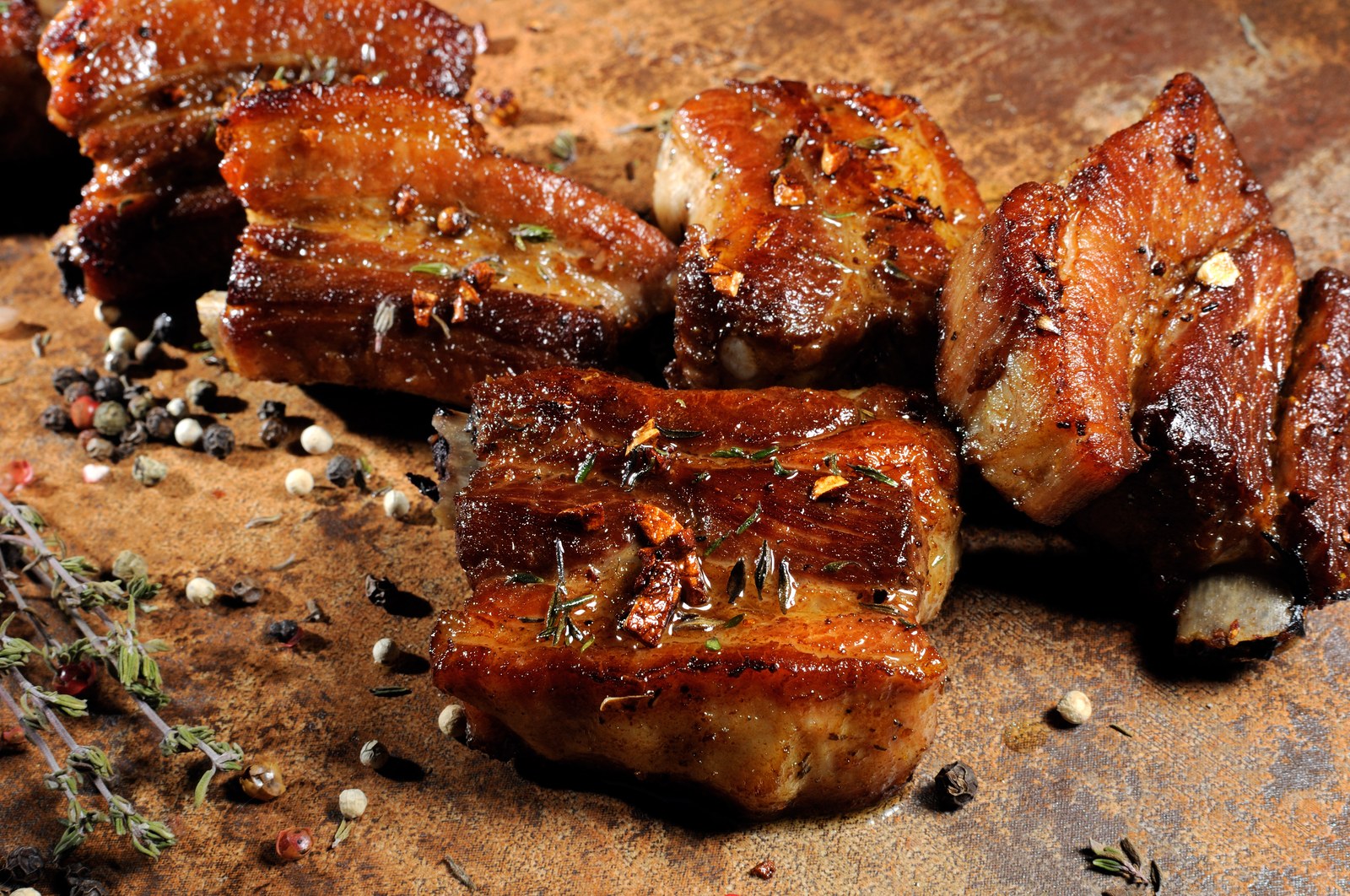 Thick-cut pork chops with caramelized glaze, fresh thyme, mixed peppercorns, deep brown sear on rustic cutting board