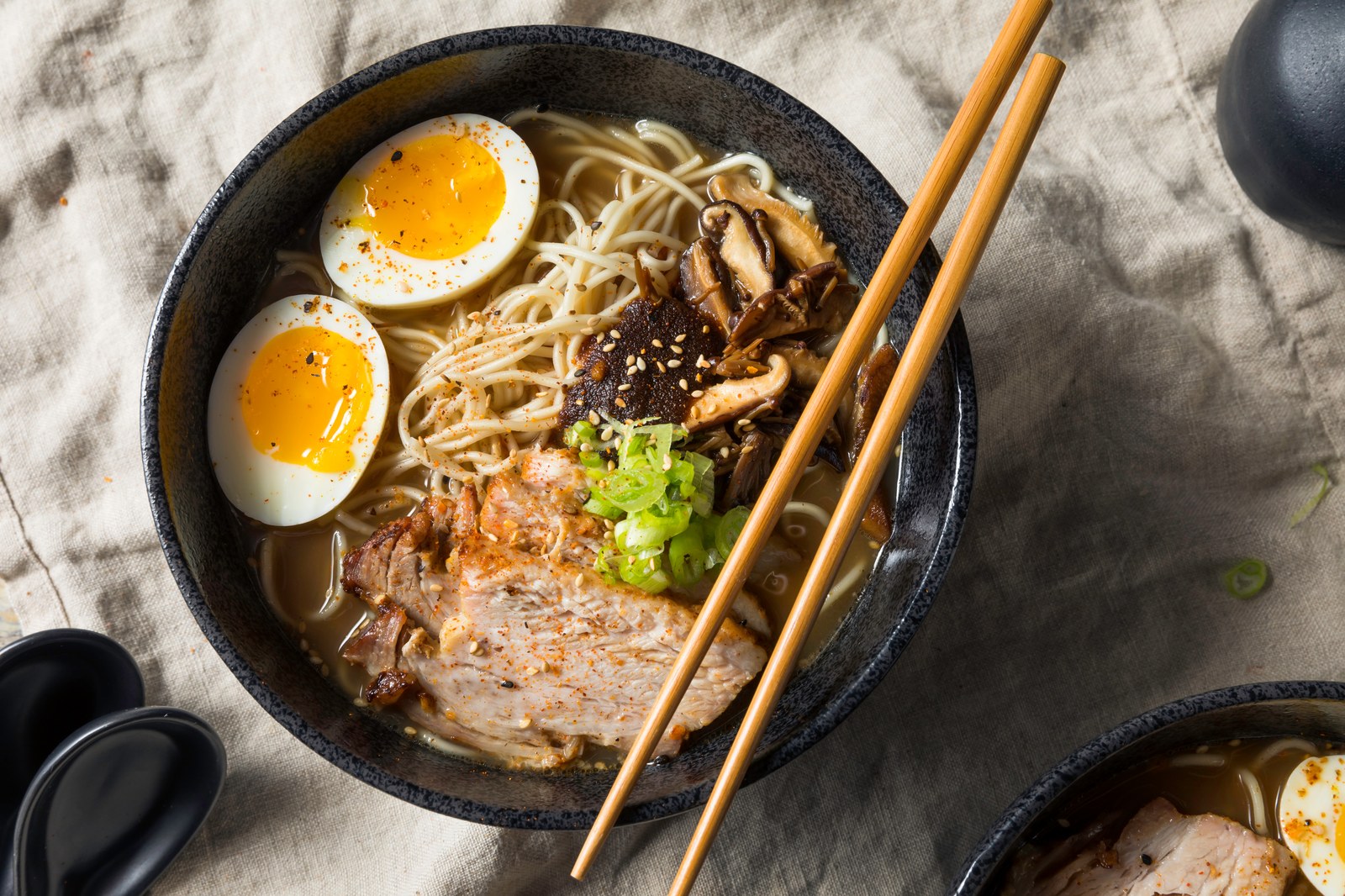 Japanese tonkotsu ramen with creamy pork bone broth, chashu pork belly slices, soft-boiled egg, bamboo shoots, noodles in dark bowl